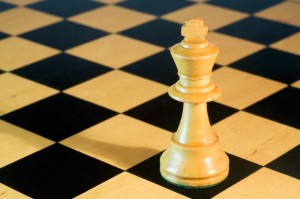 white wooden chess king on wooden chessboard closeup