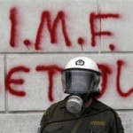 A Greek riot policeman stands in front of graffiti during violent demonstrations over austerity measures in Athens